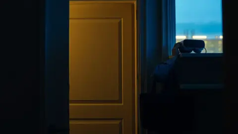 Office worker at an apartment door in the evening reaching for a VR headset