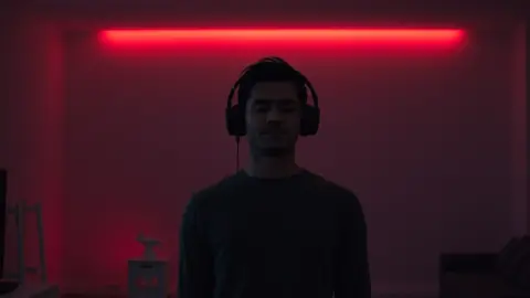 Player standing calmly in a dim living room with a red glow behind them