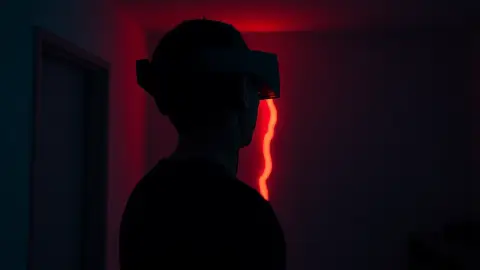 Person in a Quest headset in a dark apartment as red light glows through a crack in the wall
