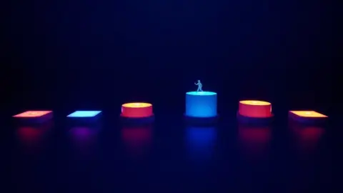 Seven glowing stepping stones in different colours rising across a dark floor with a small figure stepping up