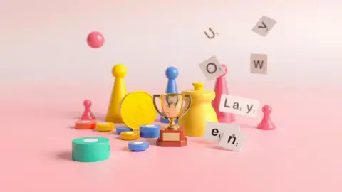 Colourful game pieces and word cards arranged around a small trophy