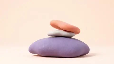Three colorful smooth stones balanced in a stack on a pale background