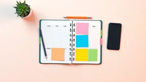 Flat-lay of a weekly planner with colored tabs, pencil and phone