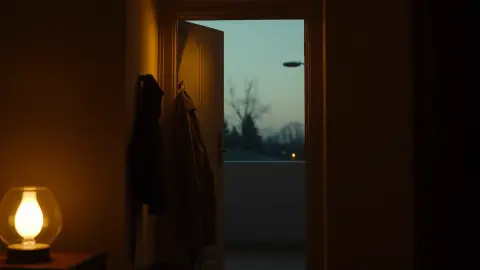 Hallway with coat, bag and a glowing lamp as someone arrives home in the evening