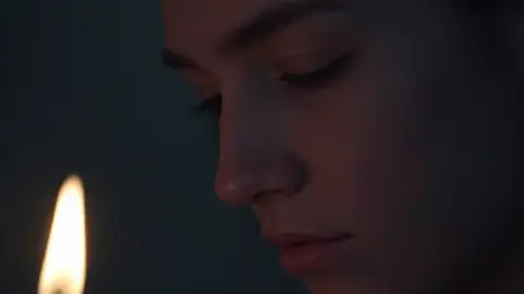 Candle flame softly glowing in a dim room