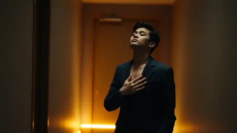 Person breathing calmly in a backstage corridor before stepping out to speak