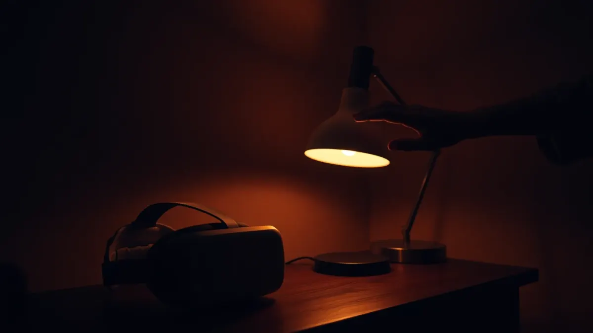 Hand switching on a lamp beside a VR headset in a dim room