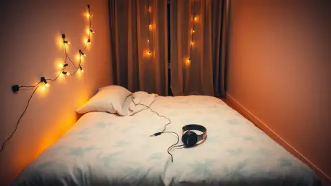Small studio apartment with a cleared patch of floor and a headset on the bed